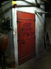 a red door with graffiti on it that says keep closed at all times